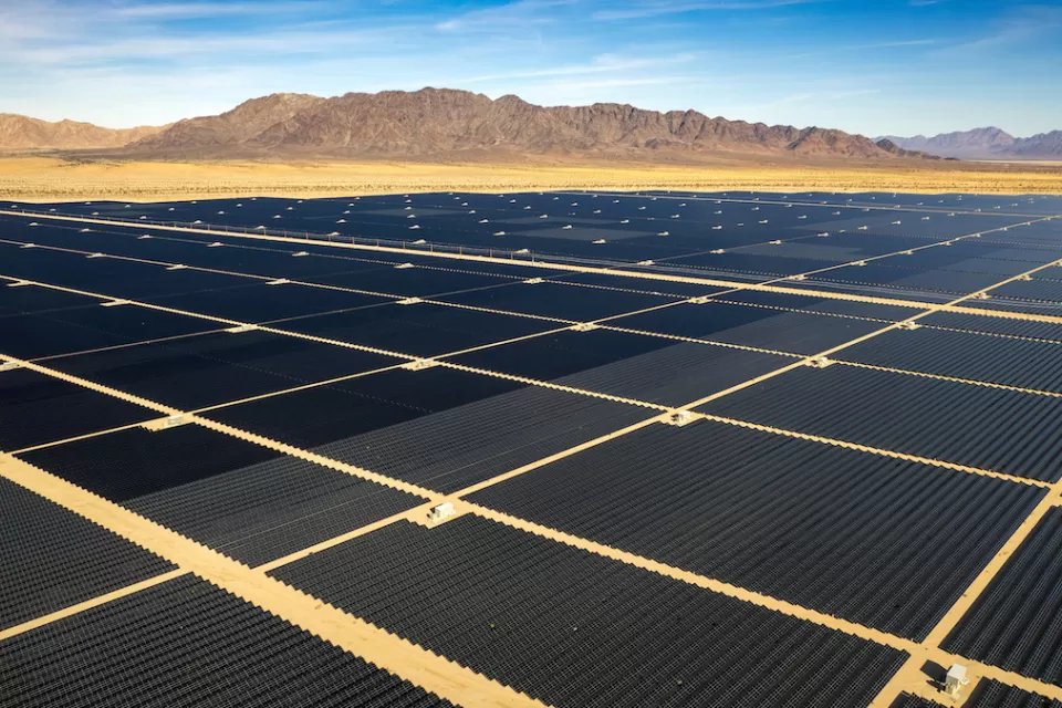 Large solar panel field in the Mojave Desert with desert mountains in background.